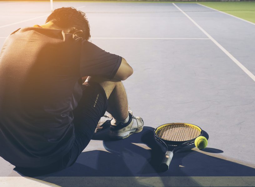 Sad tennis player sitting in the court after lose a match Sad tennis player sitting in the court after lose a match